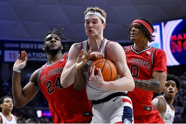 UConn forward Liam McNeeley, center, grabs a rebound between St. John's forward Zuby Ejiofor, left, and St. John's guard Aaron Scott, right, in the first half of an NCAA college basketball game, Friday, Feb. 7, 2025, in Storrs, Conn. (AP Photo/Jessica Hill)