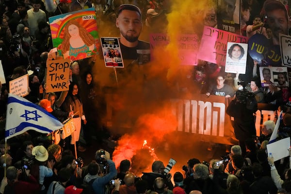 Demonstrators wave flags and signs during a protest demanding a cease-fire deal and the immediate release of hostages held in the Gaza Strip by Hamas, in Tel Aviv, Israel, Saturday, Jan. 11, 2025. (AP Photo/Ariel Schalit)