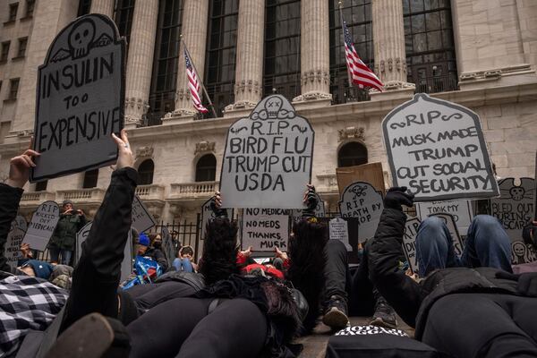 People hold signs depicting tombstones while staging a die-in outside the New York Stock Exchange during a "March to Stop the Cuts" demonstration, Saturday, March 15, 2025, in New York. (AP Photo/Yuki Iwamura)