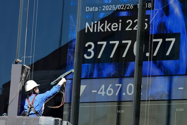 A worker wipes the glass window in front of an electronic stock board showing Japan's Nikkei index at a securities firm Wednesday, Feb. 26, 2025, in Tokyo. (AP Photo/Eugene Hoshiko)