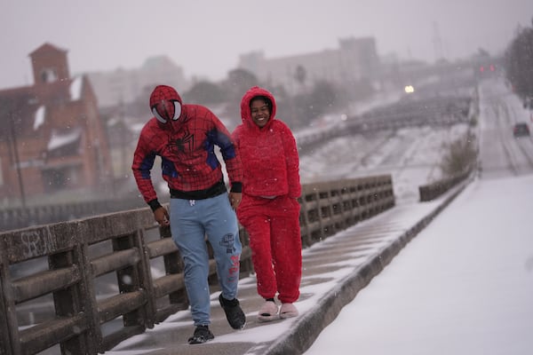 Abel Allen, in a Spider-Man suit, and Angel Tircuit walk on a snow covered bridge in New Orleans, Tuesday, Jan. 21, 2025. (AP Photo/Gerald Herbert)