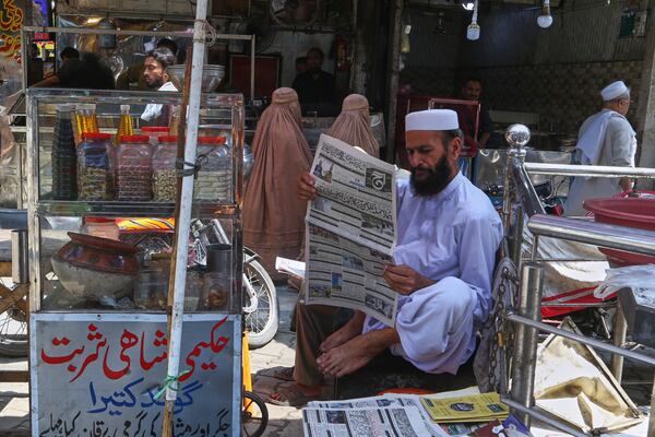 A Pakistani man reads morning news paper with front page story about Pakistan and India military tension, at a market in Peshawar, Pakistan, Friday, May 9, 2025. (AP Photo/Muhammad Sajjad)
