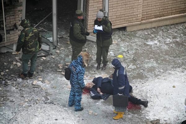 EDS NOTE: GRAPHIC CONTENT - Investigators stand near the body of Lt. General Igor Kirillov, the head of Russia's Nuclear, Biological, and Chemical Defence Forces after he and his assistant were killed by an explosive device planted close to a residential apartment's block in Moscow, Russia, Tuesday, Dec. 17, 2024. (AP Photo)