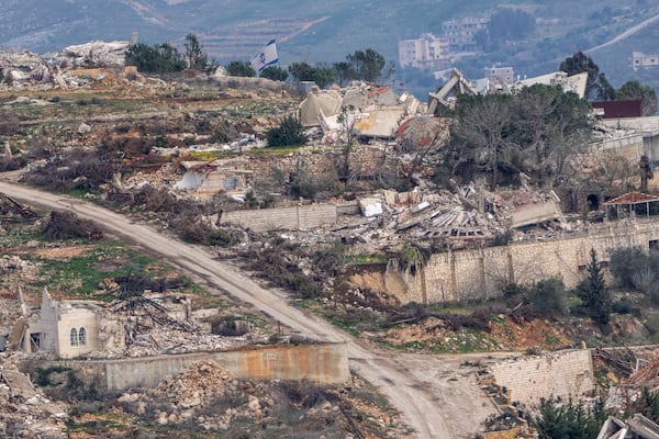 An Israeli flag floats next to destroyed buildings in southern Lebanon, as seen from northern Israel, Sunday, Jan. 26, 2025. (AP Photo/Ariel Schalit)