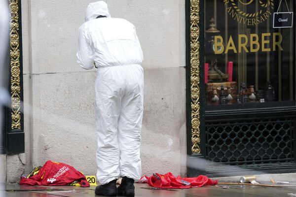 A Forensic officer looks at evidence near the site where a 53-year-old British man plowed a minivan into a crowd of Liverpool soccer fans who were celebrating the city's Premier League championship Monday, injuring more than 45 people in Liverpool, England, Tuesday, May 27, 2025.(AP Photo/Jon Super)