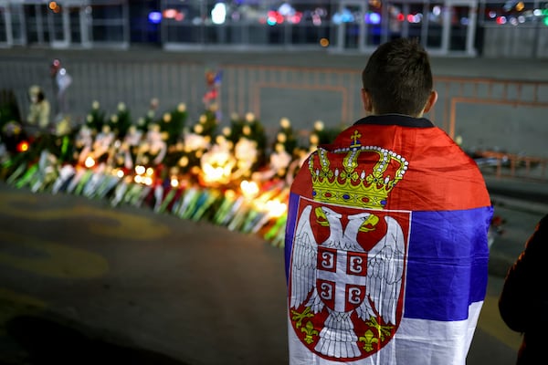 A boy wrapped in the Serbian flag stands at the site of the collapse of a concrete canopy that killed 15 people more than two months ago, during a protest in Novi Sad, Serbia, Friday, Jan. 31, 2025. (AP Photo/Armin Durgut)