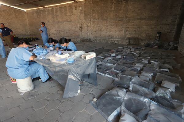 This photo released by the Jalisco State Attorney General's Office shows investigators classifying objects found at the Izaguirre Ranch, where skeletal remains were discovered, in the municipality of Teuchitlan, Mexico, Tuesday, March 11, 2025. (Jalisco State Attorney General's Office via AP)