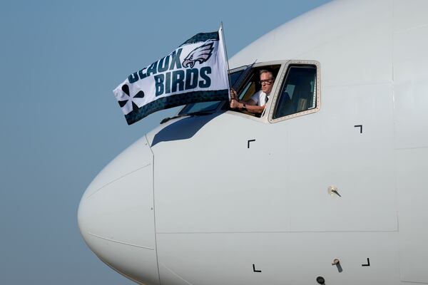 A member of the flight crew waves a Philadelphia Eagles flag after arriving at New Orleans international airport, Sunday, Feb. 2, 2025, in Kenner, La. ahead of the NFL Super Bowl 59 football game between the Philadelphia Eagles and the Kansas City Chiefs. (AP Photo/David J. Phillip)