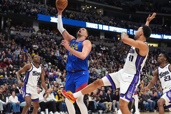 Denver Nuggets center Nikola Jokic, center, drives to the basket between Sacramento Kings guard De'Aaron Fox, left, and forward Trey Lyles in the second half of an NBA basketball game Thursday, Jan. 23, 2025, in Denver. (AP Photo/David Zalubowski)