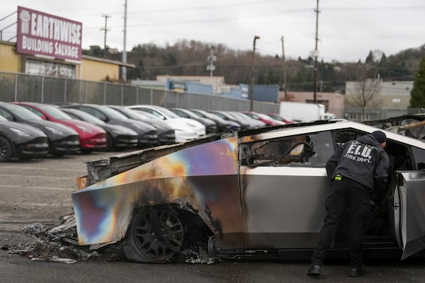 FILE - A member of the Seattle Fire Department inspects a burned Tesla Cybertruck at a Tesla lot in Seattle, Monday, March 10, 2025. (AP Photo/Lindsey Wasson, File)