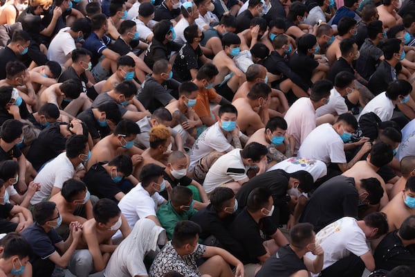 People from China, Vietnam and Ethiopia, believed to have been trafficked and forced to work in scam centers, sit with their faces masked while in detention after being released from the centers in Myawaddy district in eastern Myanmar, Wednesday, Feb. 26, 2025. (AP Photo/Thanaphon Wuttison)