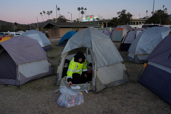 Enzo Aranda, with the San Diego facilities department, reorganizes his tent in the first responder's tent sleeping area, Thursday, Jan. 16, 2025, at the Rose Bowl Stadium in Pasadena, Calif. (AP Photo/Carolyn Kaster)