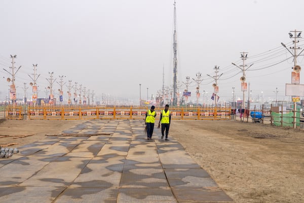 Sanitation workers walk after cleaning an area on the banks of the Ganges river, where the 45-day-long Maha Kumbh festival will officially begin on Monday, in Prayagraj, India, Sunday, Jan. 12, 2025. (AP Photo/Ashwini Bhatia)