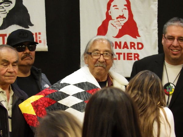 Leonard Peltier, center, a Native American activist released from a Florida prison where he had been serving a life sentence in the 1975 killings of two FBI agents, dons a star quilt while surrounded by Turtle Mountain tribal council representatives during a welcome event, Wednesday, Feb. 19, 2025, at the Sky Dancer Casino Resort near Belcourt, N.D., on the Turtle Mountain Reservation. (AP Photo/Jack Dura)