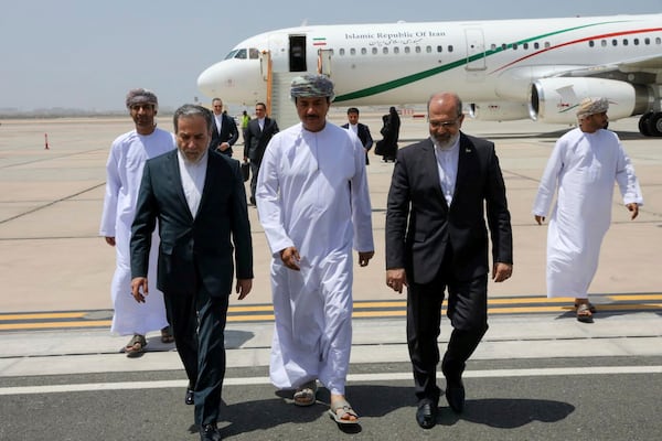 In this photo released by the Iranian Foreign Ministry, Iranian Foreign Minister Abbas Araghchi, left, is welcomed by an unidentified Omani official, center, upon his arrival at Muscat, Oman, for negotiations with U.S. Mideast envoy Steve Witkoff, as Iranian Ambassador to Oman Mousa Farhang walks at right, Sunday, May 11, 2025. (Iranian Foreign Ministry via AP)