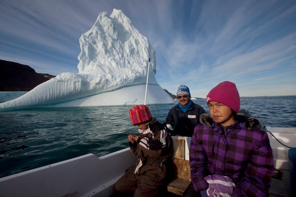 FILE - In this July 21, 2011 photo, Inuit hunter Nukappi Brandt steers his small boat as he and his daughter Aaneeraq, 9, scan the water for seals, accompanied by his other daughter Luusi, 8, outside Qeqertarsuaq, Disko Island, Greenland. (AP Photo/Brennan Linsley, file)