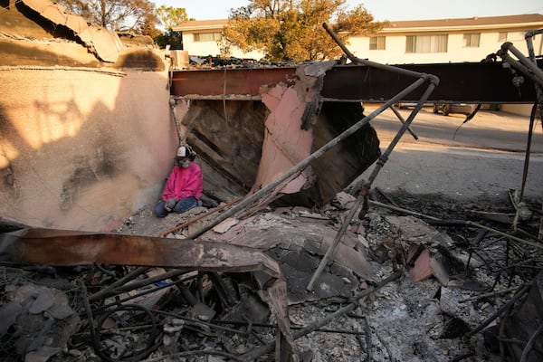 Kaegan Baron takes a moment as she sifts through the rubble of her mother's home after it was destroyed by the Palisades Fire in the Pacific Palisades neighborhood of Los Angeles, Saturday, Jan. 11, 2025. (AP Photo/John Locher)