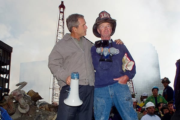 FILE — As rescue efforts continue in the rubble of the World Trade Center in New York, President George W. Bush, left, stands with New York City firefighter Bob Beckwith on a burnt fire truck in front of the World Trade Center during a tour of the devastation, Sept. 13, 2001. (AP Photo/Doug Mills, File)