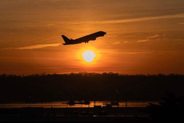 The sun rises and a jet lifts off above a wreckage site in the Potomac River from Ronald Reagan Washington National Airport, Monday, Feb. 3, 2025, in Arlington, Va. (AP Photo/Jose Luis Magana)