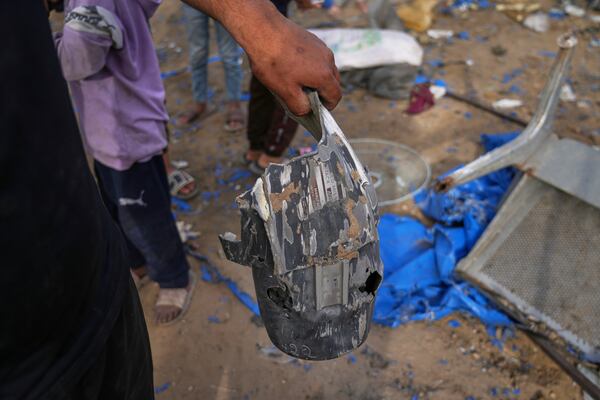 A man holds a piece of an explosive device as Palestinians inspect the damage caused by an Israeli strike that hit tents near Al-Aqsa Hospital in Deir al-Balah, in the central Gaza Strip, Saturday, May 17, 2025. (AP Photo/Abdel Kareem Hana)