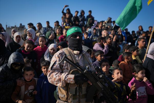 A Hamas fighter stands next to a crowd as before the hand-over of Israeli and Thai hostages to the Red Cross in the south Gaza Strip town of Khan Younis, Thursday Jan. 30, 2025.(AP Photo/Abdel Kareem Hana)