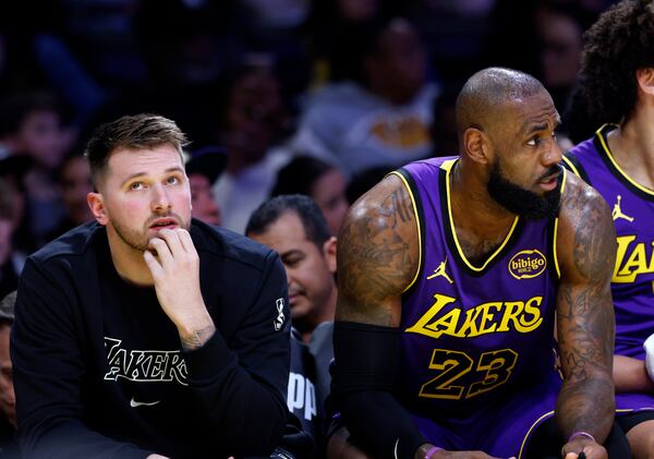 Los Angeles Lakers guard Luka Doncic, left, and forward LeBron James (23) look on from the bench during the first half of an NBA basketball game against the Golden State Warriors, Thursday, Feb. 6, 2025, in Los Angeles. (AP Photo/Kevork Djansezian)