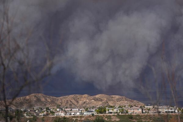 A large plume of smoke caused by the Hughes Fire rises from Castaic Lake as seen from a neighborhood of Santa Clarita, Calif., Wednesday, Jan. 22, 2025. (AP Photo/Marcio Jose Sanchez)