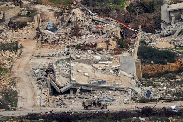 An Israeli military vehicle drives past destroyed buildings in a village in southern Lebanon, as seen from northern Israel, Sunday, Jan. 26, 2025. (AP Photo/Ariel Schalit)