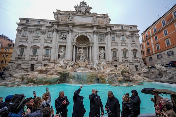 FILE - Rome's mayor Roberto Gualtieri, center, tosses a coin into the 18th century Trevi Fountain, one of Rome's most iconic landmarks, as it reopens to the public after undergoing maintenance, just on time for the start of the Jubilee Year, an event expected to draw millions of visitors to the Eternal City, in Rome, Sunday, Dec. 22, 2024. (AP Photo/Andrew Medichini, File)