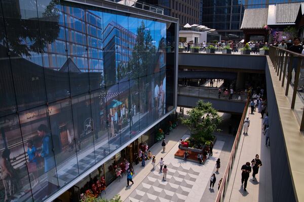 People tour by a projector screen promoting a newly opened outdoor Hutong style shopping mall, in Beijing, Monday, May 26, 2025. (AP Photo/Andy Wong)