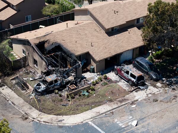 Debris covers the ground after a small plane crashed into a San Diego neighborhood, setting homes and cars on fire and forcing evacuations early Thursday, May 22, 2025. (AP Photo/William Liang)