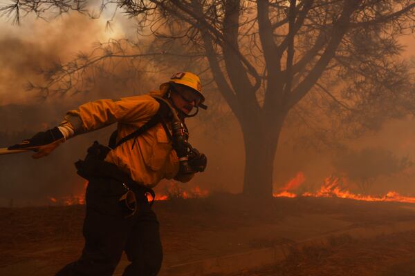 A firefighter battles the advancing Palisades Fire in the Pacific Palisades neighborhood of Los Angeles, Tuesday, Jan. 7, 2025. (AP Photo/Etienne Laurent)