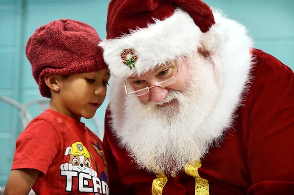 Zane Castello, 6, whispers his Christmas wish to Santa Claus during the Winter Day Camp holiday party at the Greater Johnstown Community YMCA in Johnstown, Pa. on Monday, Dec. 23, 2024. (Thomas Slusser/The Tribune-Democrat via AP)