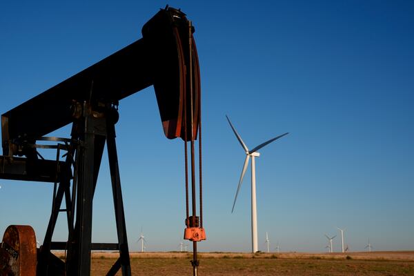 FILE - Pumpjacks operate in the foreground while wind turbines at the Buckeye Wind Energy wind farm rise in the distance, Sept. 30, 2024, near Hays, Kan. (AP Photo/Charlie Riedel, File)