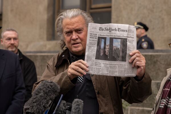 Steve Bannon shows a front page of the New York Times while speaking to reporters outside court in New York, Tuesday, Feb. 11, 2025. (AP Photo/Yuki Iwamura)