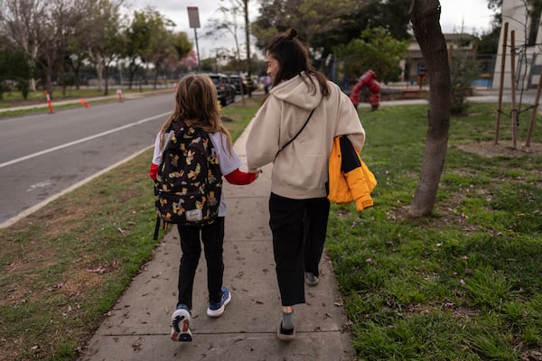 Eaton Fire evacuee Alyson Granaderos, right, walks with her son, Ceiba Phillips, 11, after picking him up from school in Pasadena, Calif., Wednesday, Feb. 5, 2025. (AP Photo/Jae C. Hong)