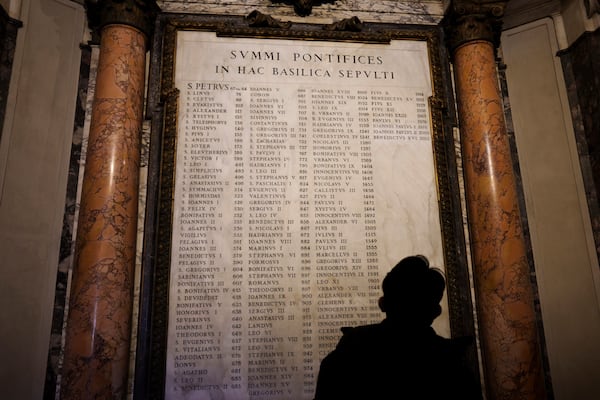 A man looks at a memorial stone inside St. Peter's Basilica at The Vatican, Friday, Feb. 28, 2025, bearing the names of the Roman Catholic pontiffs who have been buried there. (AP Photo/Bernat Armangue)