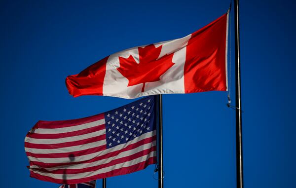 The flags of Canada and the United States fly outside a hotel in downtown Ottawa, on Saturday, Feb. 1, 2025. (Justin Tang/The Canadian Press via AP)