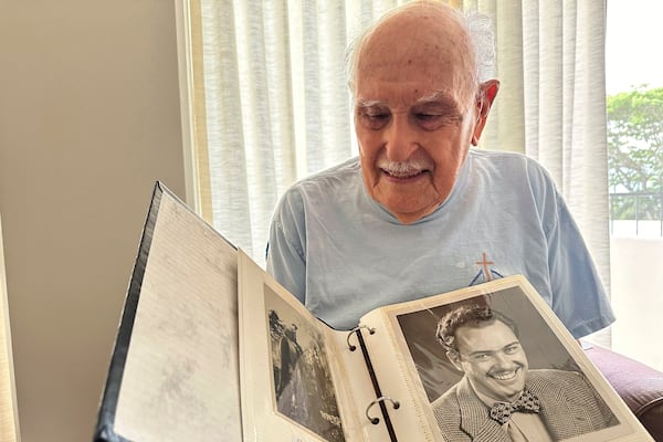 Jim Becker, a former Associated Press journalist, holds a photo album showing a 1947 photo of him as an AP reporter, at his home in Kaneohe, Hawaii, May 21, 2024. (AP Photo/Audrey McAvoy)