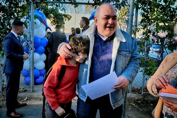 Palisades Charter Elementary School 3rd grade student Jaden Koshki cries in his father's arm Joseph Koshki upon arriving at his new school, the Brentwood Elementary Science Magnet school in the Brentwood section of Los Angeles on Wednesday, Jan. 15, 2025. (AP Photo/Richard Vogel)