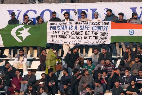 Fans hold Pakistani and Indian flags with a message banner as they watch the tri-series ODI cricket match between Pakistan and New Zealand at Gaddafi Stadium in Lahore, Pakistan, Feb. 8, 2025. (AP Photo/K.M. Chaudary)