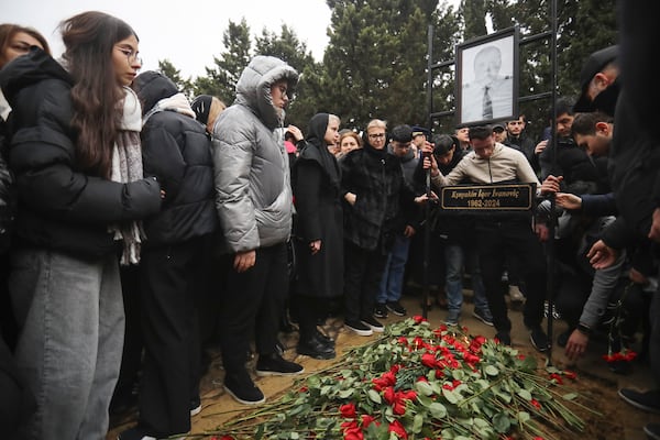 People stand at the grave of pilot in command Igor Kshnyakin during a funeral of the crew members of the Azerbaijan Airlines Embraer 190 killed in a deadly plane crash in Kazakhstan this week, at the II Alley of Honor in Baku, Azerbaijan, Sunday, Dec. 29, 2024. (AP photo)