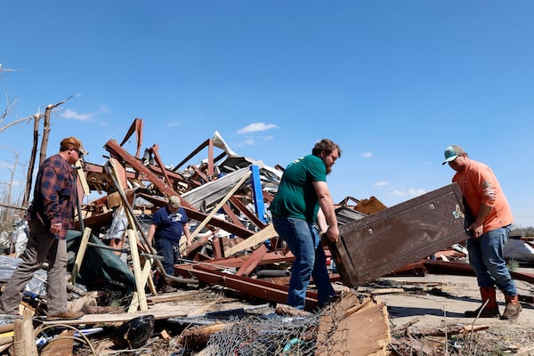 Friends and family carry off a safe from the damaged building after a tornado passed through the area, Sunday, March 16, 2025, in Plantersville, Ala. (AP Photo/Butch Dill)