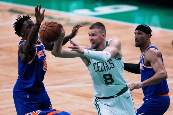 Boston Celtics center Kristaps Porzingis (8) passes the ball while pressured by the New York Knicks during the first half of Game 1 of an NBA basketball second-round playoff series Monday, May 5, 2025, in Boston. (AP Photo/Charles Krupa)
