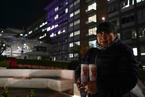 A woman holds two candles with the pictures of Pope Francis outside the Agostino Gemelli Polyclinic in Rome, Tuesday, Feb. 18, 2025, where the Pontiff was hospitalized Friday, Feb. 14, after a weeklong bout of bronchitis worsened and is receiving drug therapy for a respiratory tract infection. (AP Photo/Gregorio Borgia)