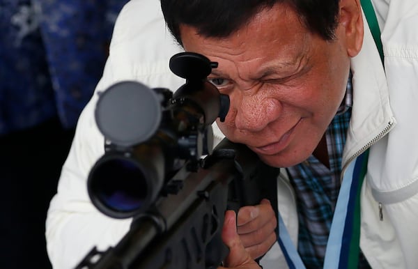 FILE - Philippine President Rodrigo Duterte checks the scope of a Chinese-made CS/LR4A sniper rifle during the presentation of thousands of rifles and ammunition by China to the Philippines at Clark Airbase in northern Philippines on June 28, 2017. (AP Photo/Bullit Marquez, File)