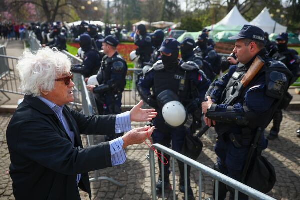 A man speaks with police officers prior to a an anti-corruption rally in Belgrade, Serbia, Saturday, March 15, 2025. (AP Photo/Armin Durgut)