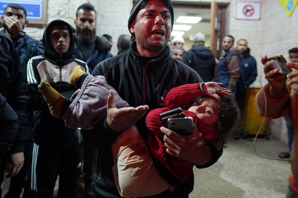 A man reacts while carrying a wounded girl to Al-Aqsa Martyrs Hospital following Israeli army airstrikes in Deir al-Balah, central Gaza Strip, Saturday Jan. 4, 2025.(AP Photo/Abdel Kareem Hana)