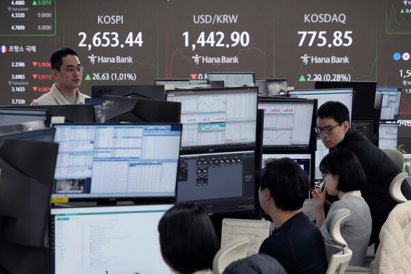 Currency traders work near a screen showing the Korea Composite Stock Price Index (KOSPI), top left, and the foreign exchange rate between U.S. dollar and South Korean won, top center, at the foreign exchange dealing room of the KEB Hana Bank headquarters in Seoul, South Korea, Wednesday, Feb. 19, 2025. (AP Photo/Ahn Young-joon)