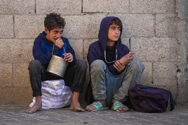 Two Palestinian boys wait to collect donated food at a food distribution center in Deir al-Balah, central Gaza Strip, Thursday Jan. 2, 2025. (AP Photo/Abdel Kareem Hana)